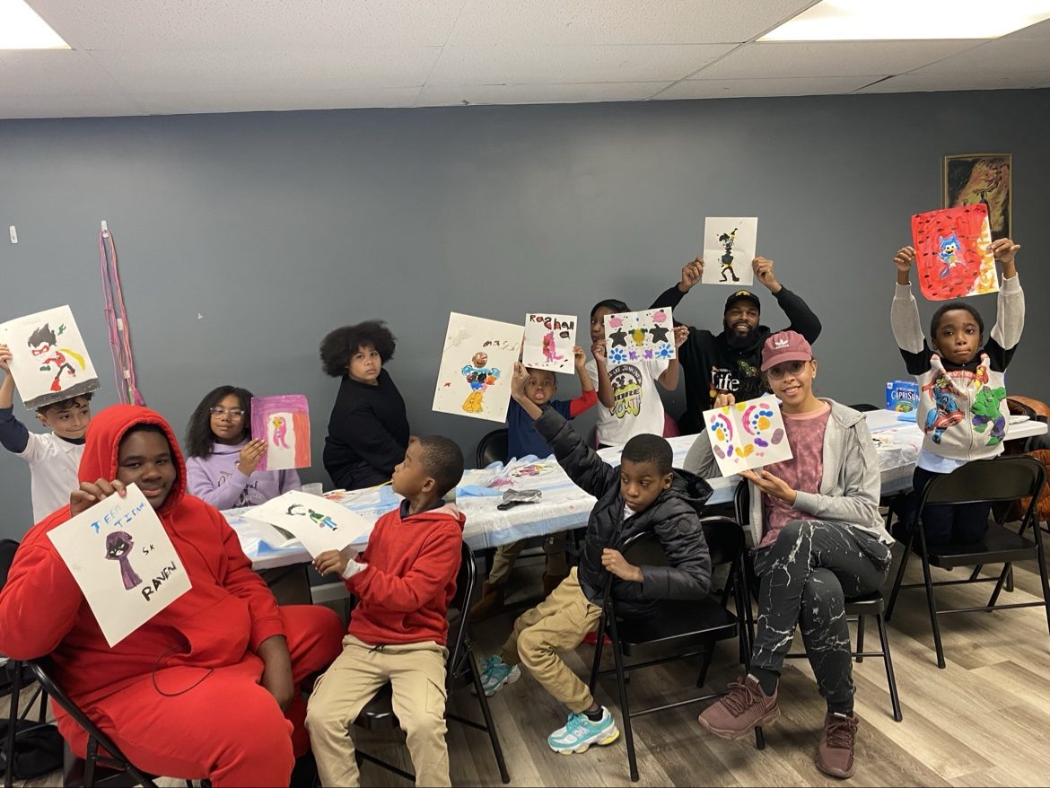Young artists holding up their paintings at an art workshop